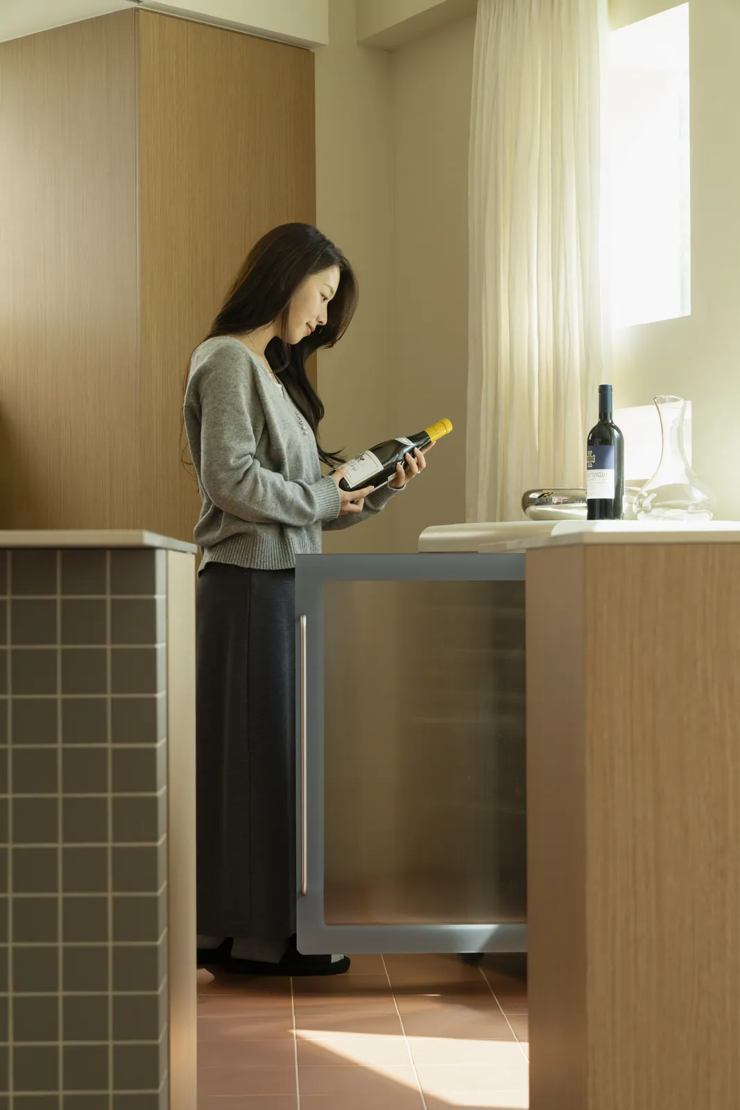 Checking a bottle from the wine cellar beside a kitchen island